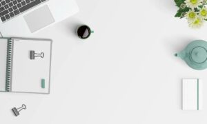 flat lay photography of macbook pro beside white spiral notebook and green mug